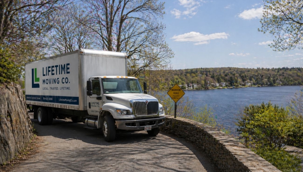 A moving truck carefully navigating a narrow road overlooking Lake Quinsigamond in Shrewsbury, MA.